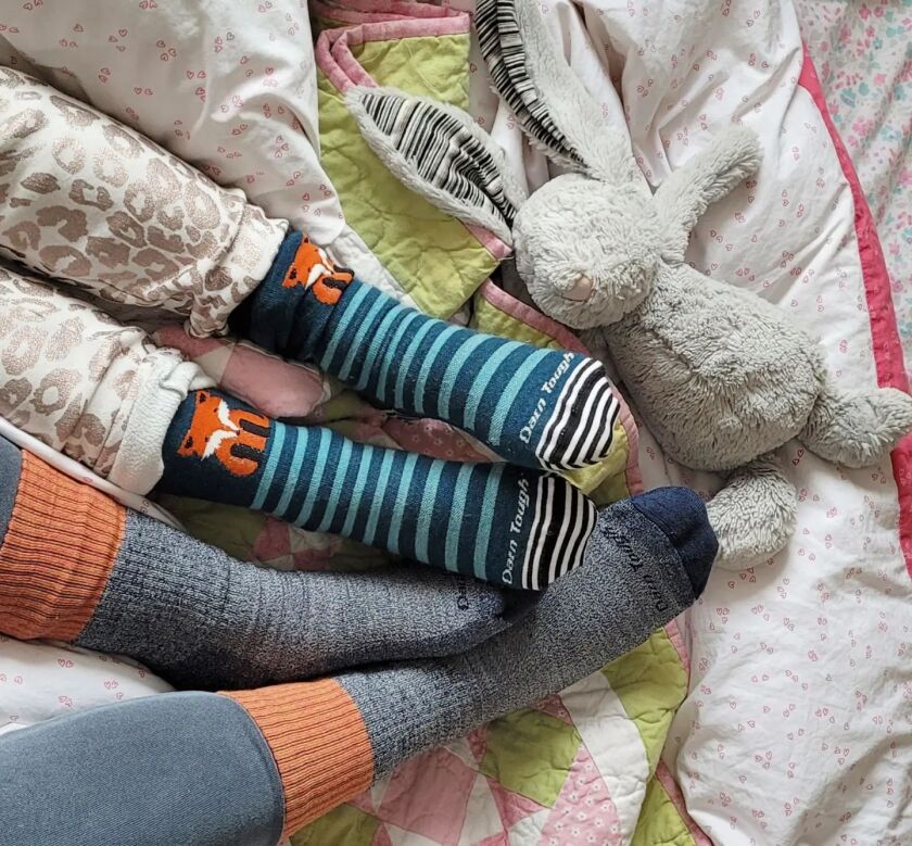 An adult and a child's feet, adorned in Darn Tough socks.