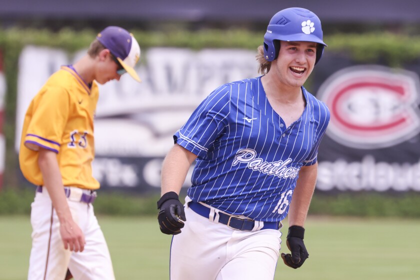 High school baseball players play on outdoor field on sunny day
