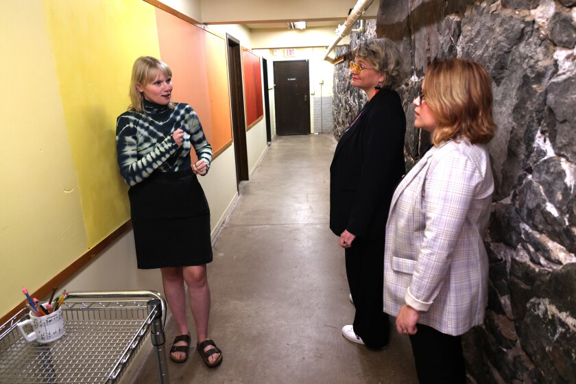 Two authors listen to source share a story in a hallway