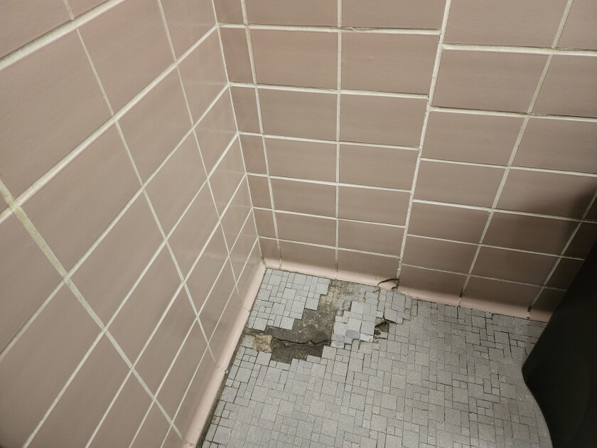 The lines of wall tile in this restroom at West Learning Center show how much the ground has settled, as does the crack in the floor tiling, shown on July 21, 2022.