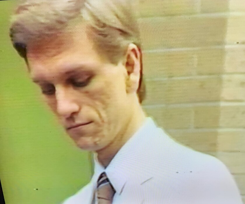 A blonde man looks downward.