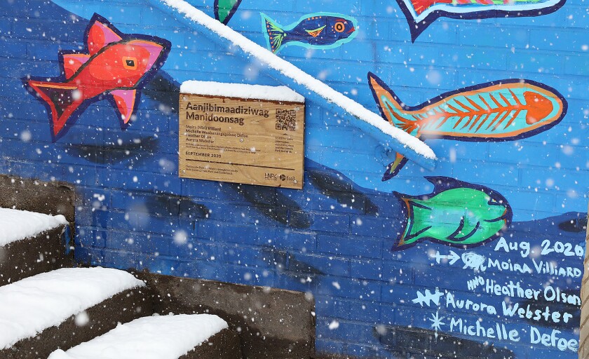 A plaque with a QR code on it is mounted on the mural titled Aanjibimaadiziwag Manidoonsag