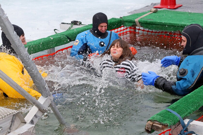 People jump into the water during the Polar Plunge event on Pelican Lake.
