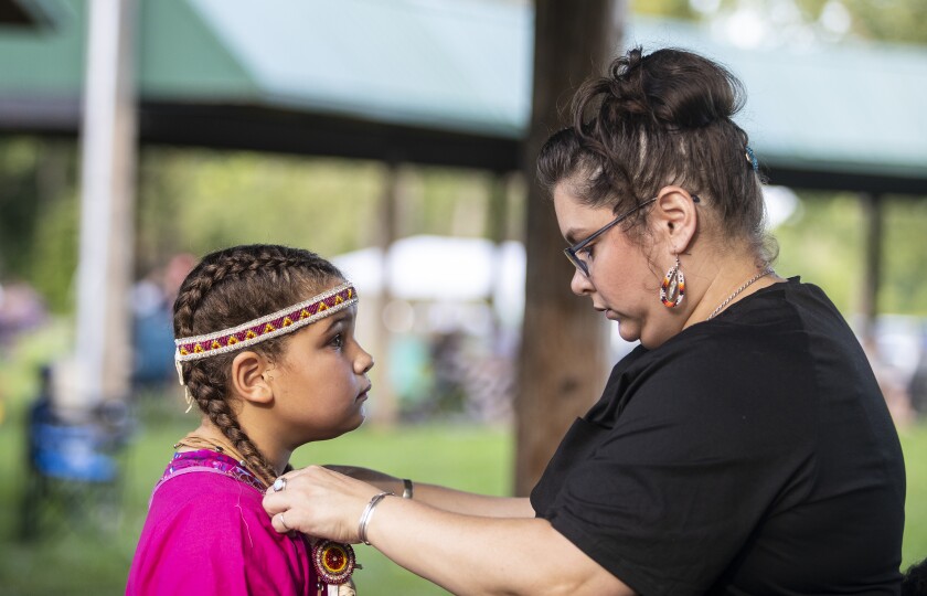 Mother Paige Matthiae, at right, adjusts the regalia of daughter Nia Shinsky, 9, as they prepare to participate in the Upper Sioux Community's traditional WACIPI on the evening of Friday, August 5, 2022.