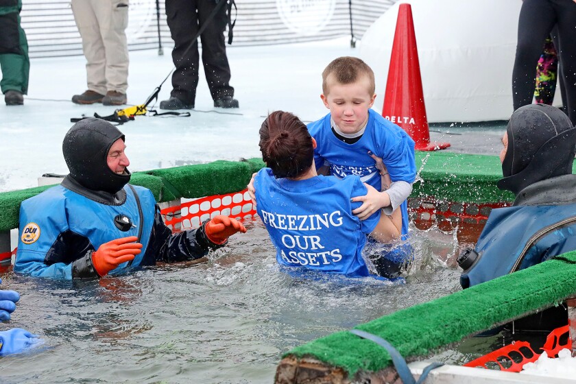 People jump into the water during the Polar Plunge event on Pelican Lake.