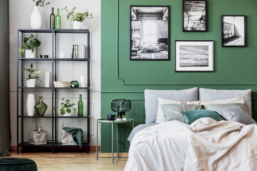 Gallery of black and white poster on green wall behind king size bed with pillows and blanket