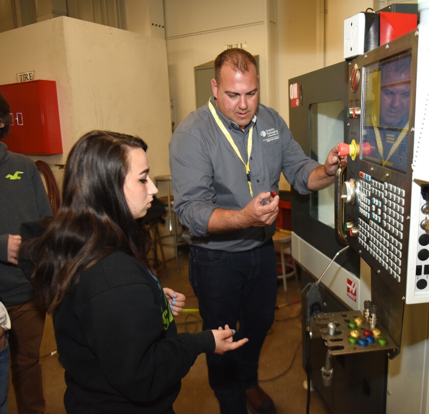 Brainerd senior Nikeska Thomas listens Tuesday to Ryan Parks, machinist with Graphic Packaging International, explain how the office mill from Haas Automation machined metal parts. Bridges Career Academies and Workplace Connection brought the sophisticated machine to the Brainerd south campus for students to learn cutting-edge technologies in manufacturing. Steve Kohls/ Brainerd Dispatch Video