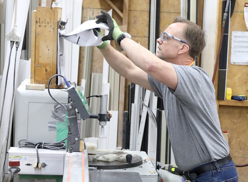 Tony Drewes checks the specs on the next set of frames he’s preparing to cut at Fentech in Superior