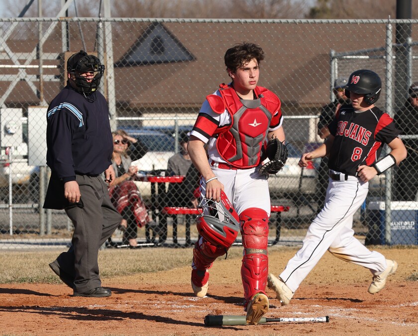 Worthington Trojans relief runner Konner Honius (8) scores a tying run as Redwood Valley catcher Riley Dikken waits for the ball during a Monday evening game.