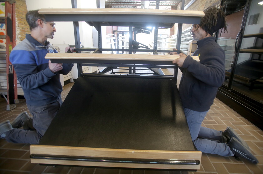 Two men working together to assemble a display shelf inside of a grocery store.
