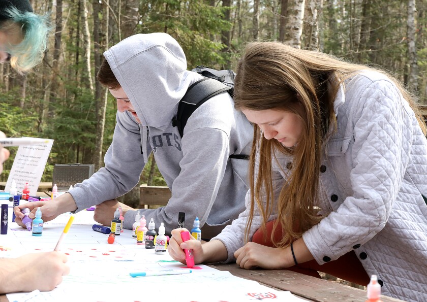 Superior High School students Robby Powell, left, and Grace Hansen sign a congratulatory banner for science teacher Lori Danz