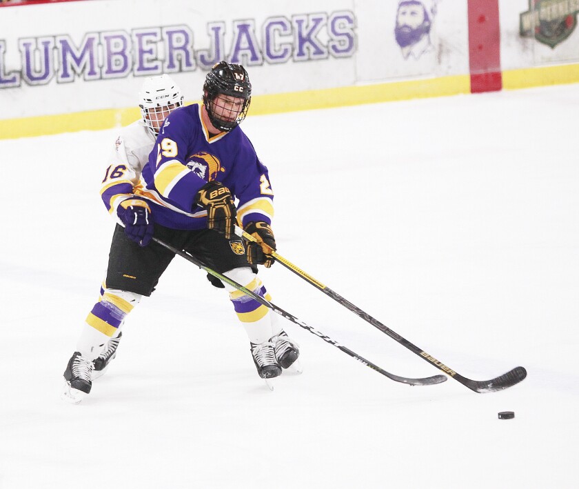 Cloquet-Esko-Carlton high school player Logan Dushkin tries to poke the puck away from alumnus Westin Michaud, a senior at Colorado College, during the annual alumni versus high school games Monday, Dec. 24. Jamie Lund/Pine Journal