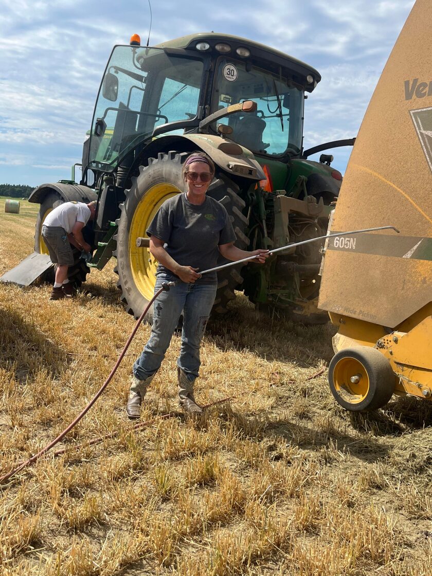 Jacki Chirstman, co-owner of JC Farms in Adams County, North Dakota, stands before a baler and tractor during a haying day.