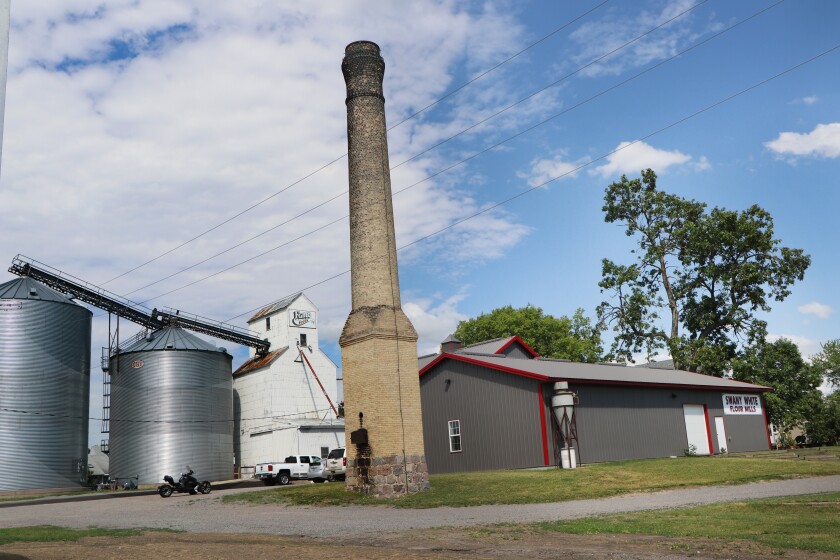 A brick smokestack stands against a new building that houses Swany White Flour Mills, Ltd.