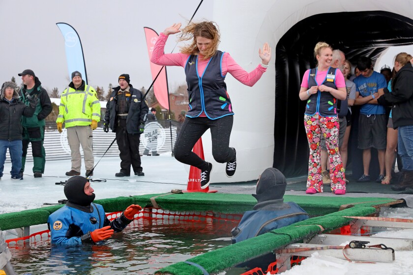 People jump into the water during the Polar Plunge event on Pelican Lake.
