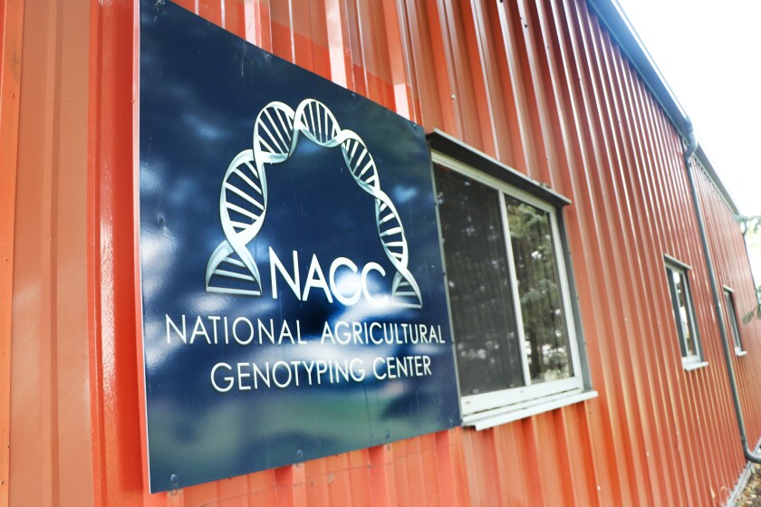 A sign for the National Agricultural Genotyping Center lab is on the exterior rust-red metal wall.