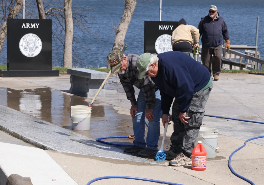 VFW members Larry Woodbary (rear left) and Jon Hait pause cleaning to remember a Nobles County veteran as they help clean Freedom Veterans Memorial Park for VFW service day Saturday morning.
