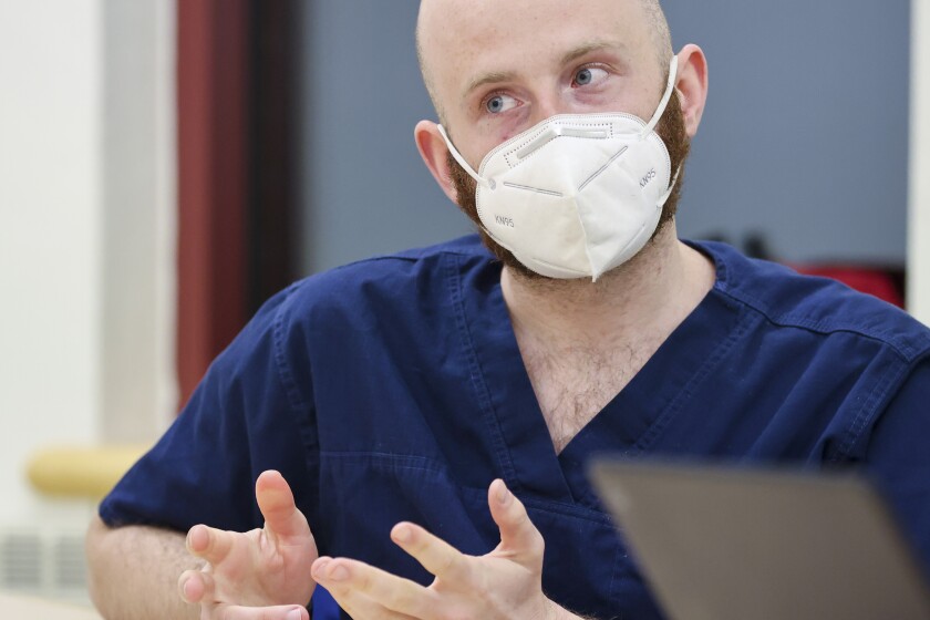 People at a meeting table with laptops and face masks