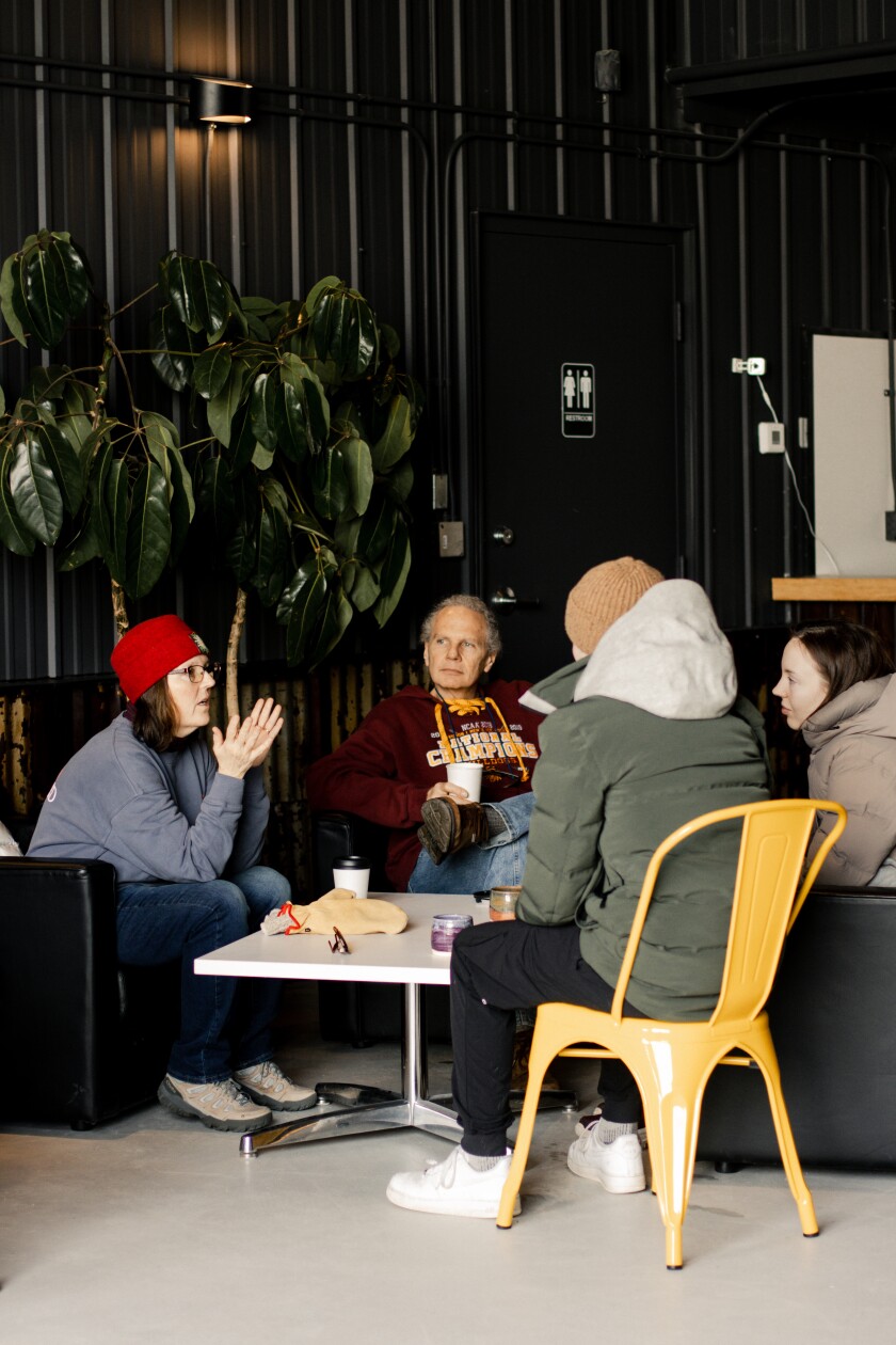 A small group of people converse at a coffee table.