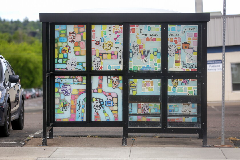 A bus shelter at an intersection in city featuring a mural.