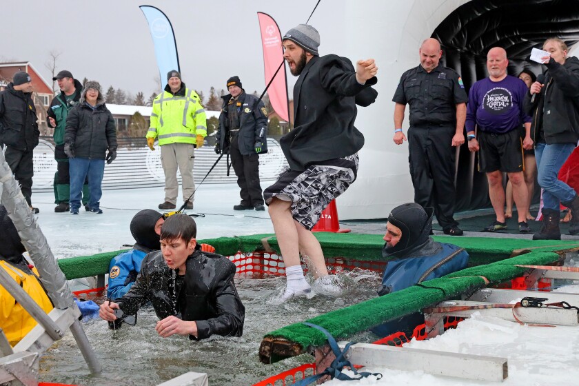 People jump into the water during the Polar Plunge event on Pelican Lake.