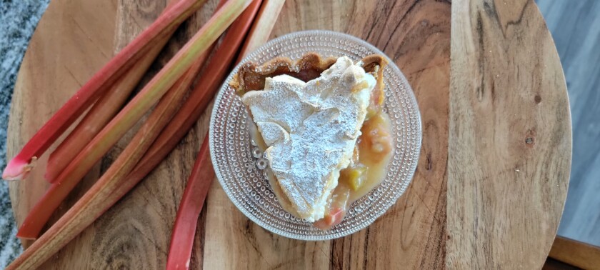 Rhubarb Meringue Pie on plate with stalks of rhubarb next to plate