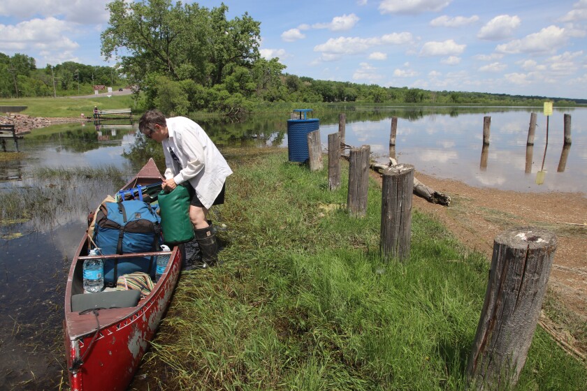 A woman loads bags into a crowded canoe.
