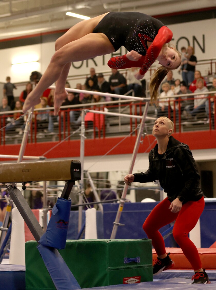 Worthiington Trojans head Coach Joni Reitmeier follows Addison Gerber's dismount during Friday night's match with New Ulm.