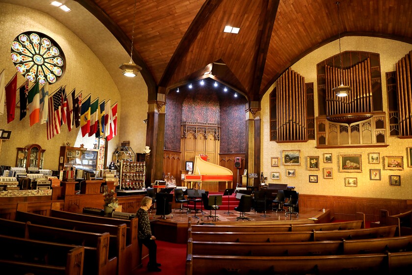 Helmi Harrington sits on the corner of a pew as she looks over the performance hall