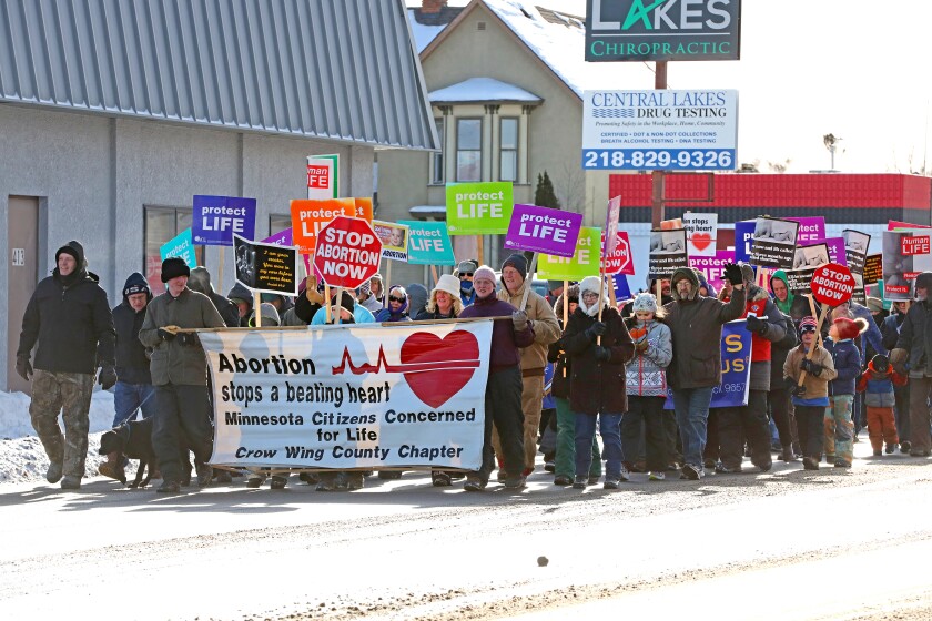 People march down the street with signs and banners.