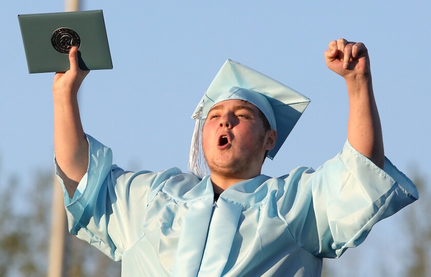 Justin Thompson celebrates his diploma as he walks down the ramp