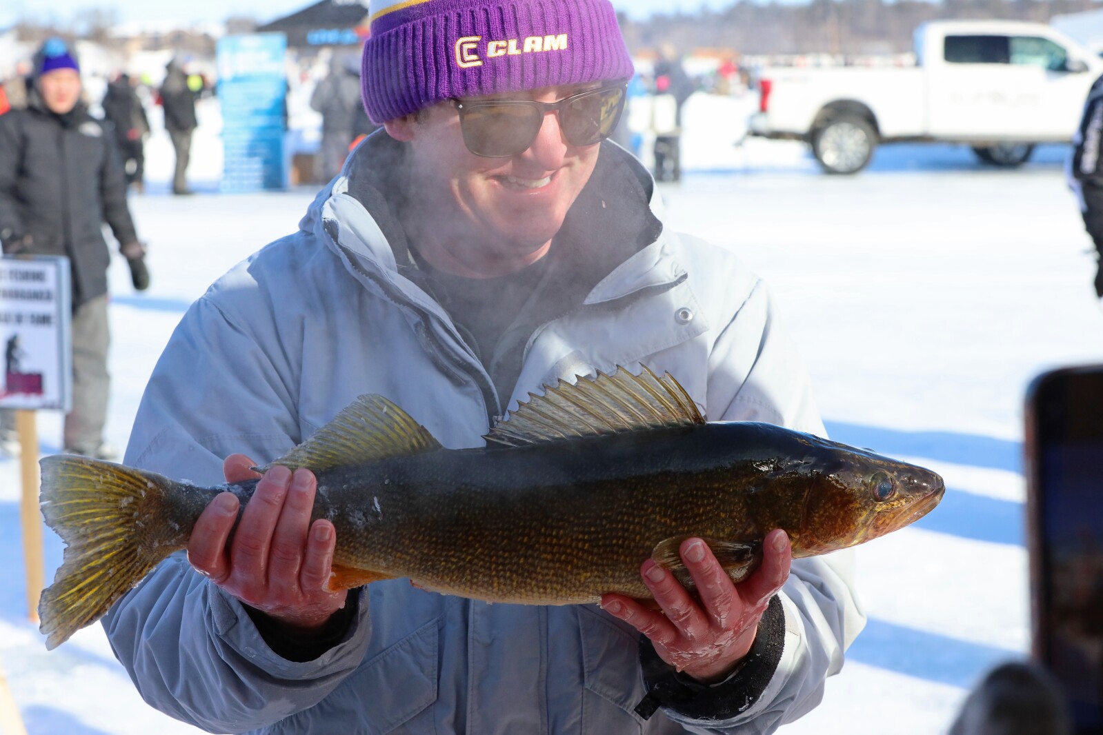 Man holds up large walleye at the weigh in tent during the ice fishing extravaganza.