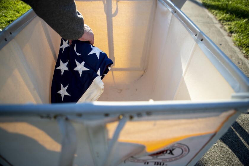 A volunteer grabs an American flag to be put out on display at the Flags of Honor Memorial in Willmar on Friday, May 27, 2022.