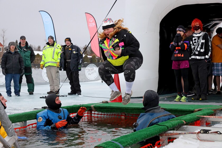 People jump into the water during the Polar Plunge event on Pelican Lake.