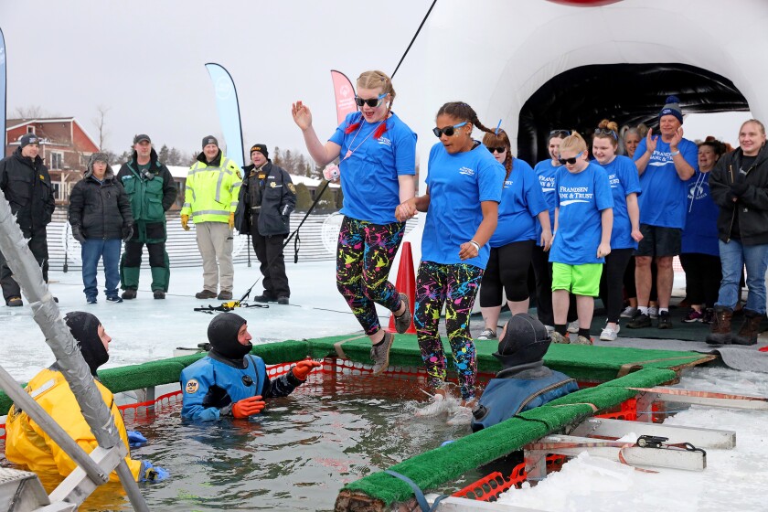 People jump into the water during the Polar Plunge event on Pelican Lake.