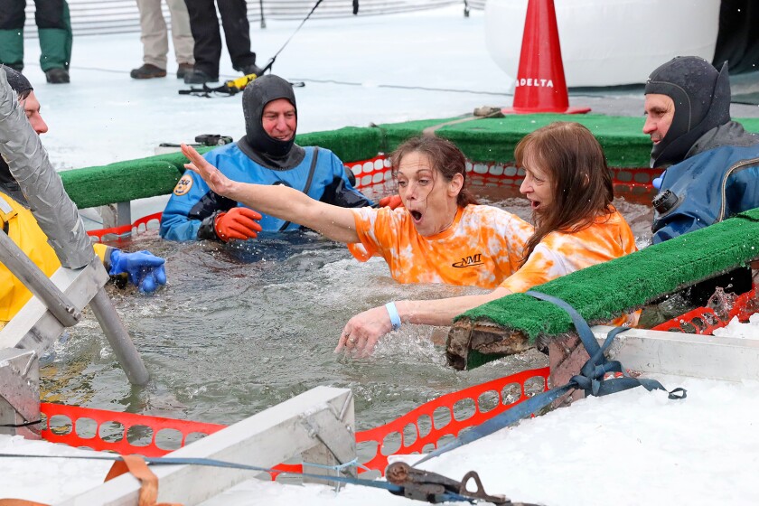 People jump into the water during the Polar Plunge event on Pelican Lake.