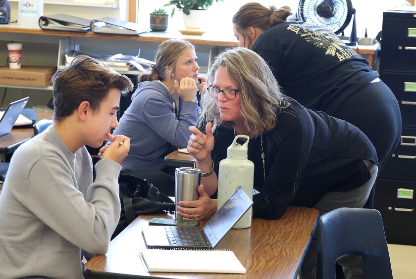 Octagon adviser, Katie Thompson, right, talks to Logan Johansen during journalism class at Northwestern High School