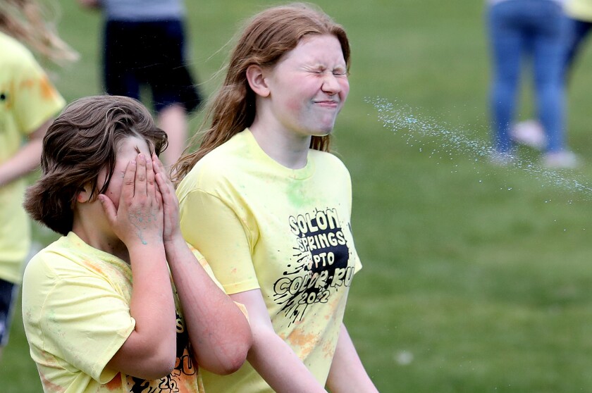 Ezra Ahlberg, left, covers up as Halle Johnson gets sprayed in the face