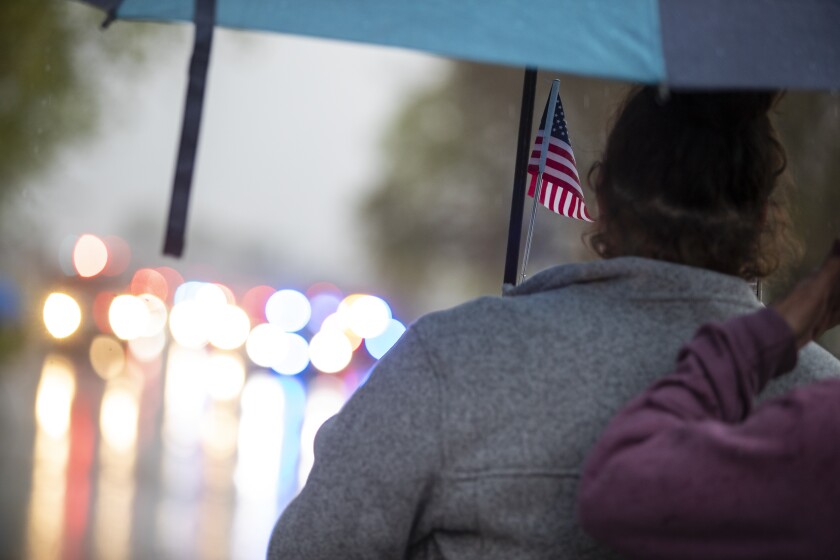 A woman holds an American flag while watching the procession of Ryan Leif Erickson move through Blomkest on Tuesday, May 17, 2022.