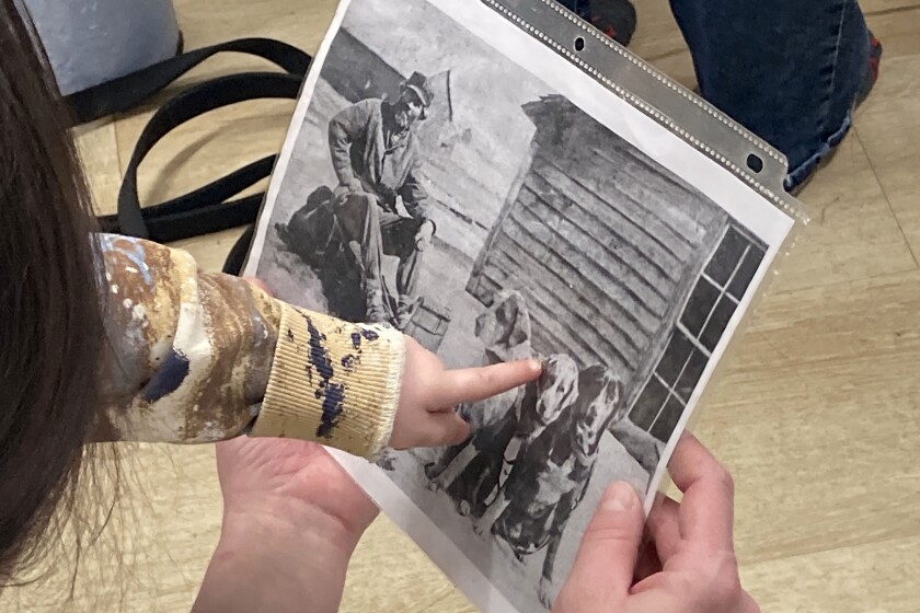 A child pointing at dogs in an old photograph.