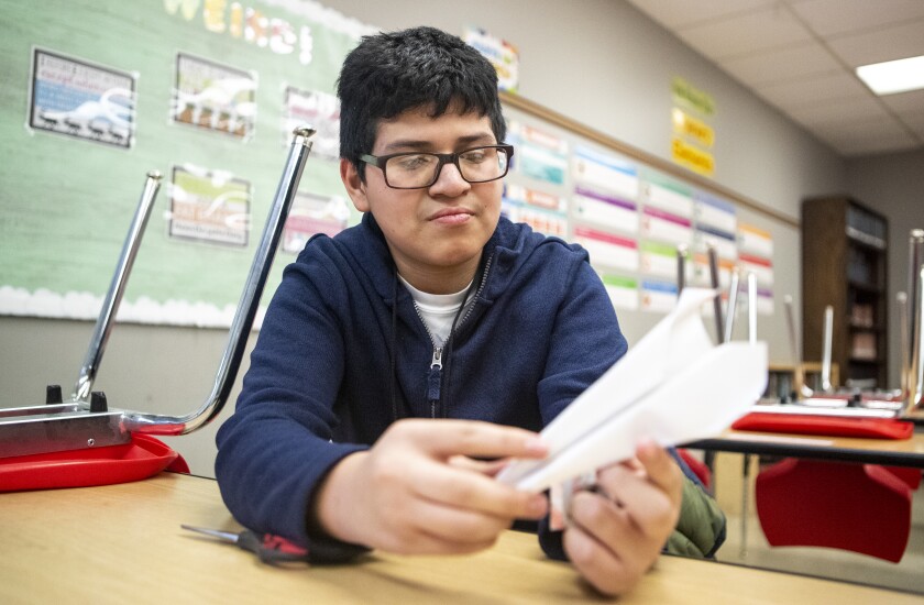 Jose Galindoo Mendoza, 12, folds a paper airplane
