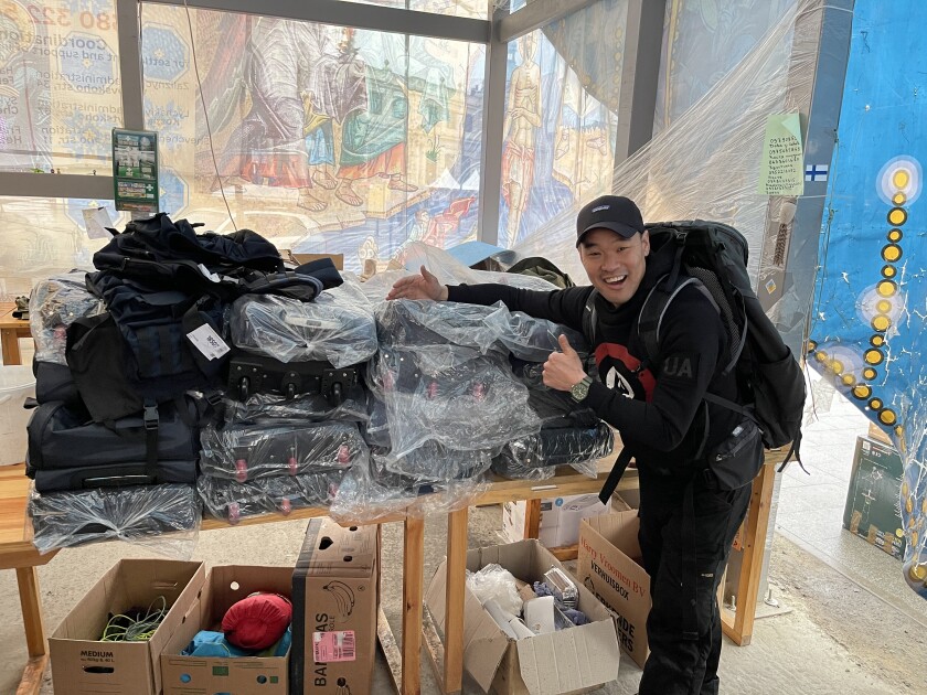 A smiling man gives a thumbs up next to a pile of wheeled luggage.