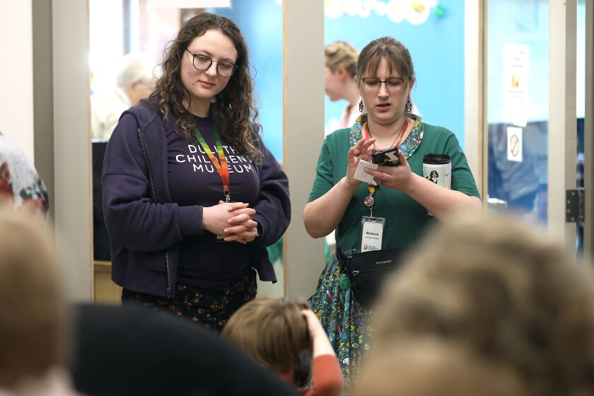 Two female museum staff members looking on during a kid's event.