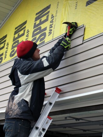 Members of A+ Roofing drive nails into a garage in Killdeer Thursday afternoon. (Press photo provided by Sydney Mook)