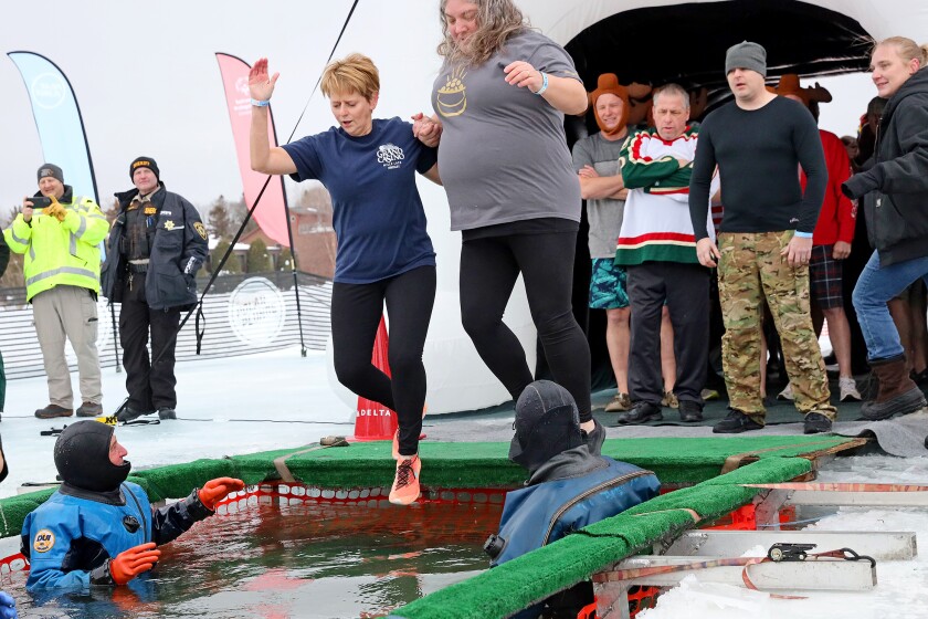 People jump into the water during the Polar Plunge event on Pelican Lake.