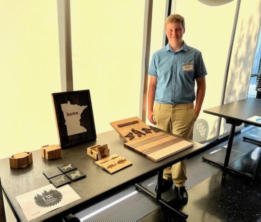 Boy stands next to handmade wooden items