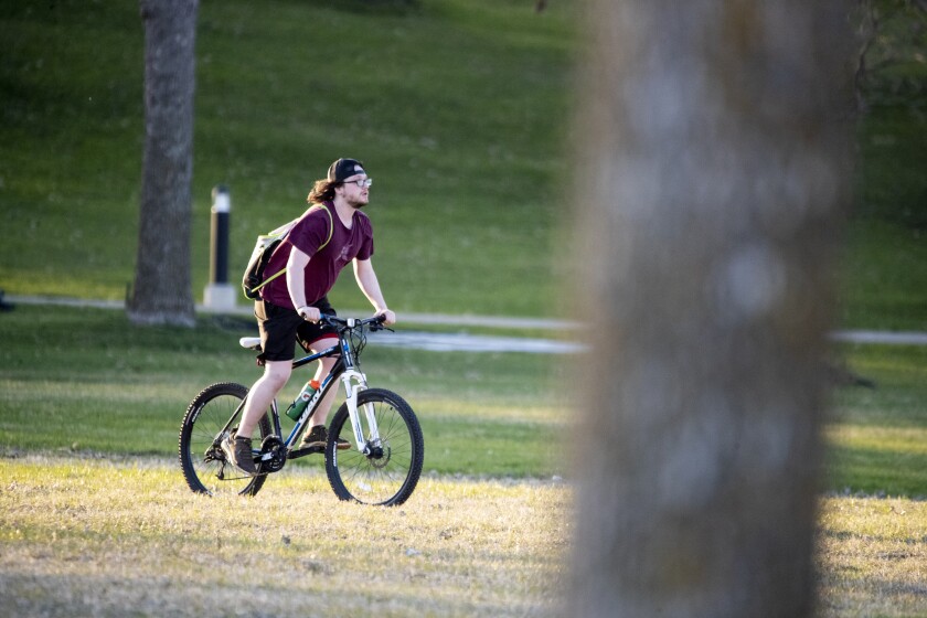 A cyclist rides through an illuminated stretch of grass at Robbins Island Regional Park in Willmar on Friday, May 6, 2022.