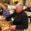 Man enjoys pizza while socializing with others at event