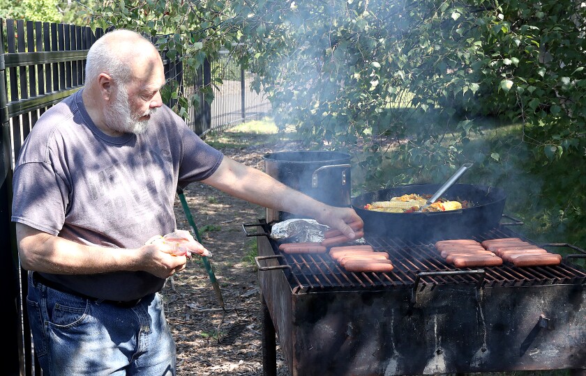 Smoke rises from the grill as Gilbert Magnuson, of Local 11 (retired), adds hot dogs during the annual Duluth AFL-CIO Labor Day Picnic