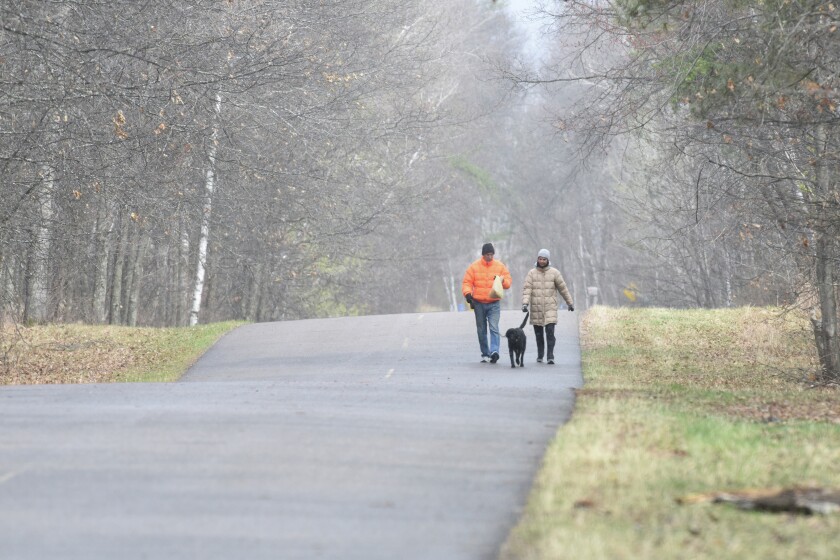As the weather fluctuated between snow showers and sunshine, Tom and Mary Polovitz walked their dog, Gracie on the Birch Grove Road Tuesday near Lake Shore. Brainerd Dispatch/Steve Kohls